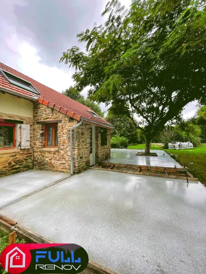 Terrasse en béton réalisée autour d'une maison en pierre par Full Renov